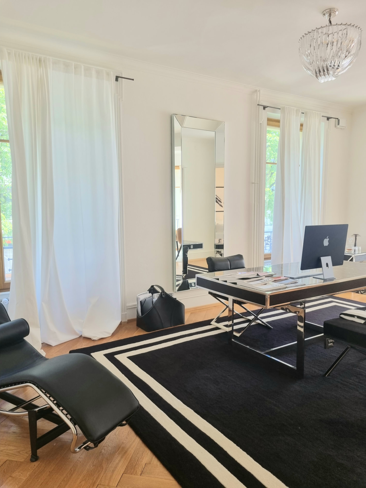 Bureau d’un appartement haussmannien à Lausanne : grand bureau, fauteuil en cuir noir et chaise longue sur parquet en point de Hongrie